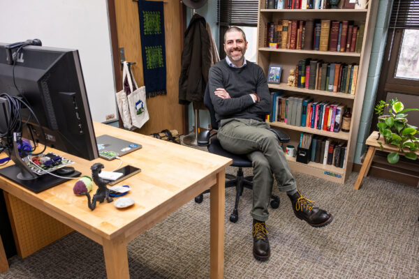 Andrew Ruis sits smiling in his office in the Educational Sciences building at UW–Madison.