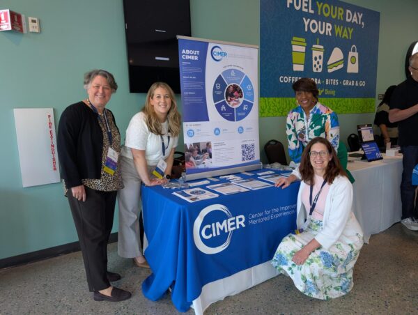 A group of directors for CIMER pose around a table at a conference.